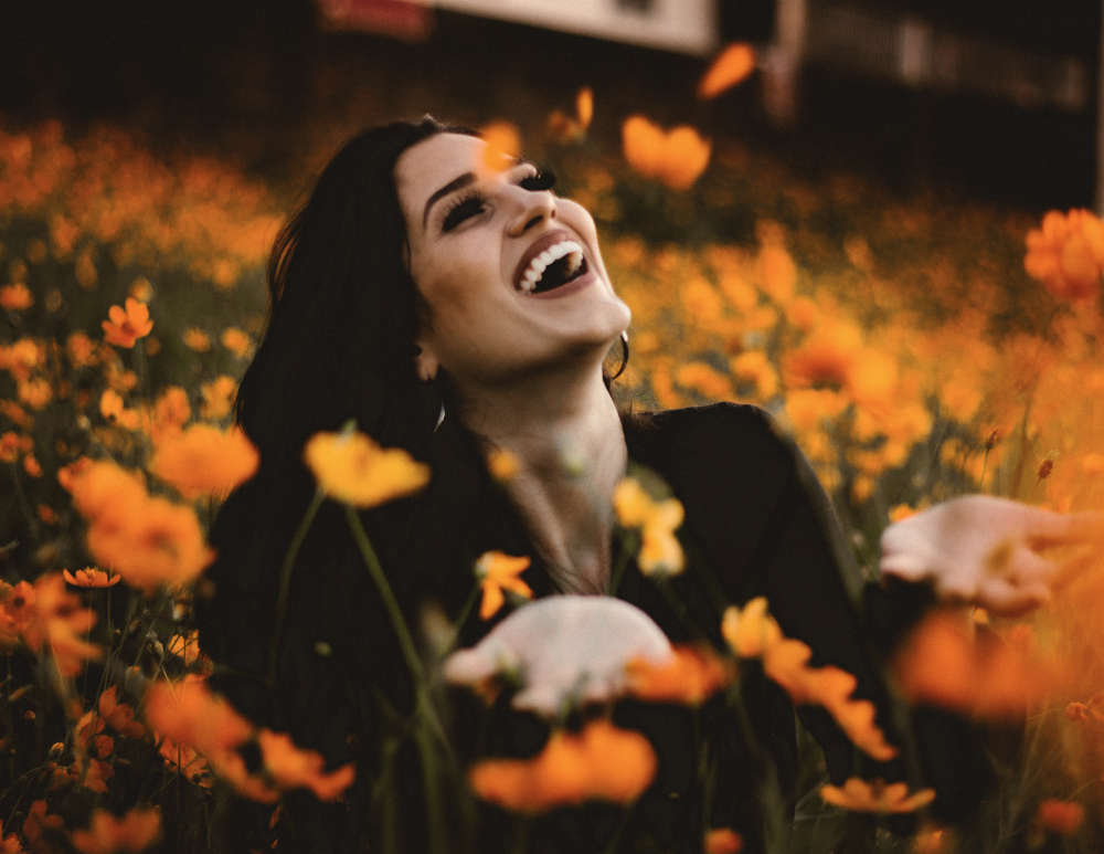 happy woman playing in a field of flowers